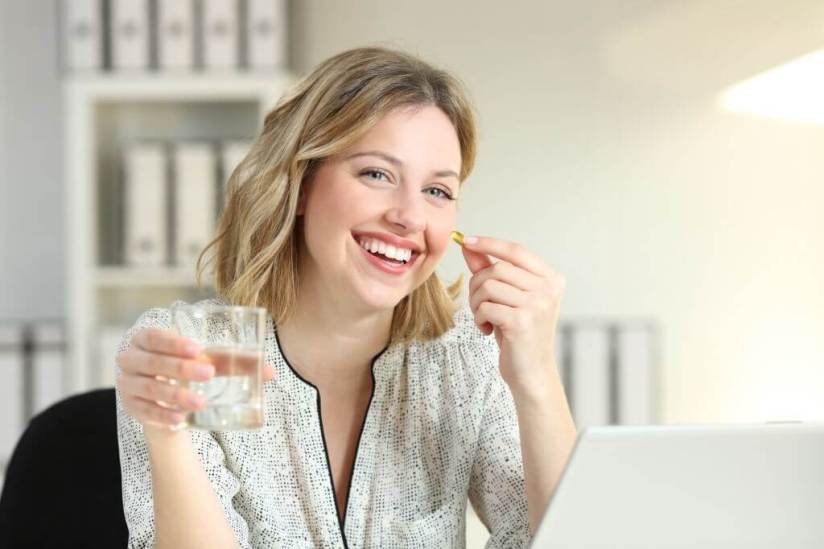 Smiley face women take a vitamin supplement